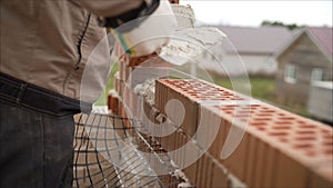 Worker puts a brick wall. Bricklayer working in construction site of a brick wall. Bricklayer putting down another row of bricks