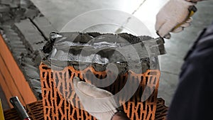 Worker puts cement on a brick on a construction site. Stock footage. Bricklayer laying bricks to make a wall, he is