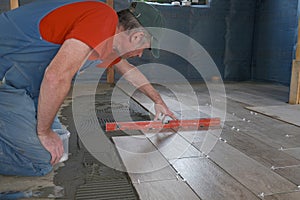 The worker puts ceramic tiles on the construction site