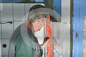 The worker puts ceramic tiles on the construction site