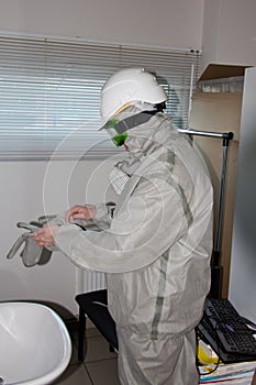 A worker puts on a chemical protection suit and cask