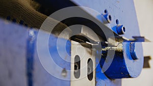 Worker puts metal plank to cutting machine tool in workshop