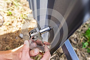 A worker puts rivets into a profiled sheet on a fence.