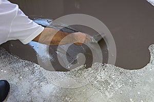 Worker puts a self leveling screed on cement floor. photo