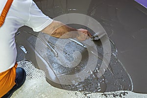 Worker puts a self leveling screed with trowel on cement floor i