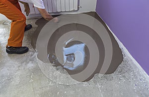 Worker puts a self leveling screed with trowel on concrete floor