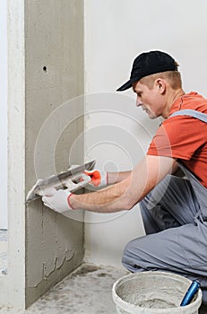 The worker puts the stucco on the wall