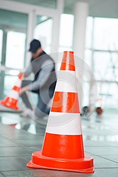 worker putting cones around area wetness on tiled floor photo
