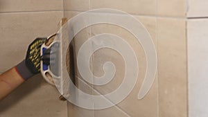 Worker putting fugue on the wall in the kitchen. Tile grouting