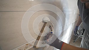 Worker putting fugue on the wall in the kitchen. Tile grouting