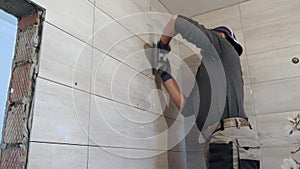 Worker putting fugue on the wall in the kitchen. Tile grouting