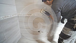Worker putting fugue on the wall in the kitchen. Tile grouting