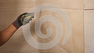 Worker putting fugue on the wall in the kitchen. Tile grouting