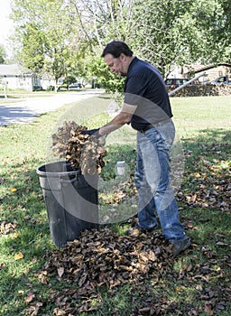 Worker Putting Leaves In Trash Can