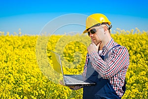 Worker in a rapeseed field doing inspection for biodiesel production