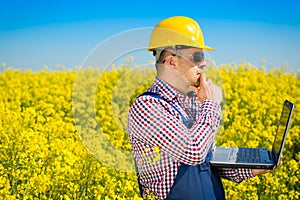 Worker in a rapeseed field doing inspection for biodiesel production