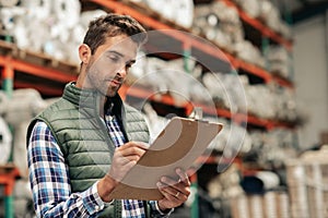 Worker reading an inventory while standing on a warehouse floor