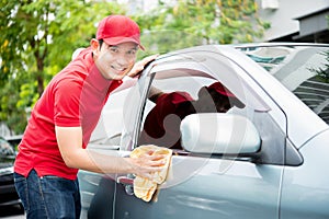 Worker in red uniform cleaning car