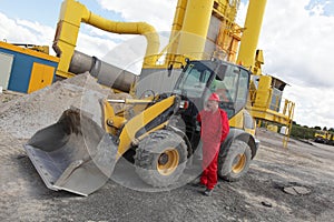 Worker in red uniform on phone at buldozer at construction site