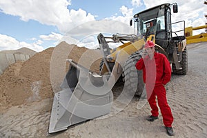 Worker in red uniform on phone at buldozer at construction site