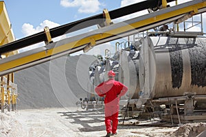 Worker in red uniform at tanks with asphalt