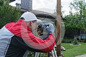 Worker  in red workwear adjusts grey engineering level.