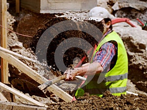 Worker with reflective vest shoveling clay