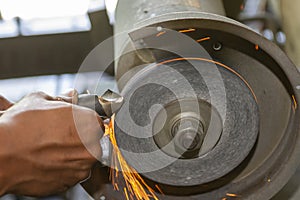 The worker regrinding the drill tool with abrasive wheel