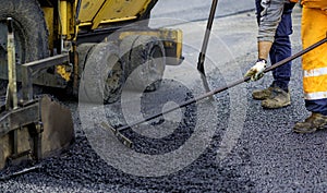 Worker regulate tracked paver laying asphalt