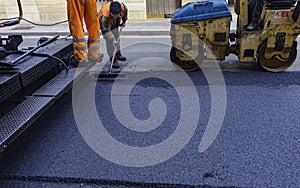 Worker regulate tracked paver laying asphalt