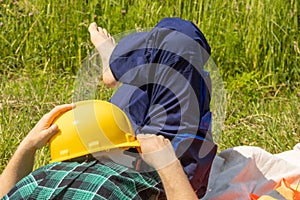 Worker relaxes lying on a meadow with a helmet and in working clothes, Concept, Work Life Balance, Balanced working and rest times