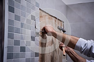 Worker remove demolish old tiles in a bathroom