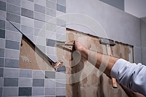 Worker remove demolish old tiles in a bathroom