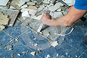 Worker remove, demolish old tiles in a bathroom with hammer and chisel