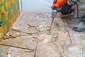 Worker remove, demolish old tiles a bathroom with jackhammer