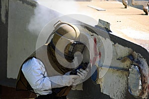 Worker is remove paint by air pressure sand blasting photo