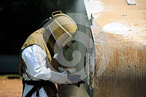 Worker is remove paint by air pressure sand blasting photo