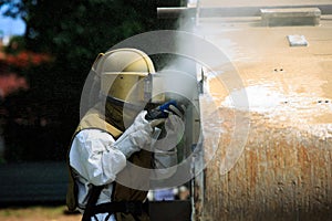 Worker is remove paint by air pressure sand blasting photo