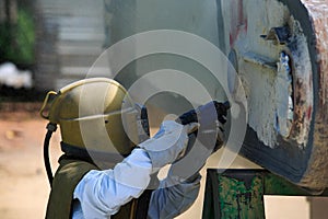 Worker is remove paint by air pressure sand blasting photo