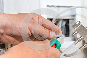 Worker removes insulation before inserting connector of a TV antenna coaxial cable to a splitter.