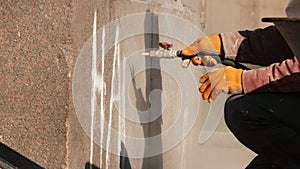 Worker removing graffiti with high pressure cleaner splashing. Cleaning wall using sandblaster gun. Professional