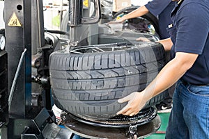 Worker removing tire from the rim using machinery at workshop