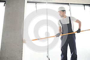 Worker renewing apartment on wall background.