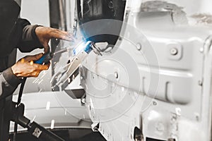 Worker repairing car body with carbon dioxide welding. Weld of auto.