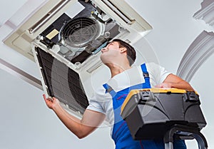 Worker repairing ceiling air conditioning unit