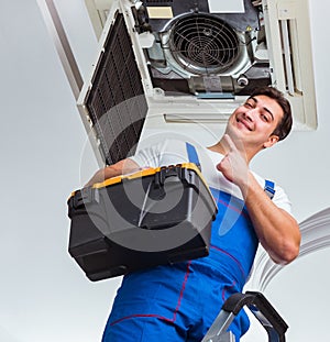 Worker repairing ceiling air conditioning unit