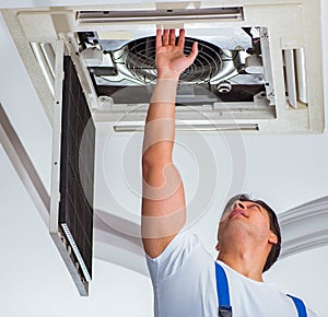 Worker repairing ceiling air conditioning unit