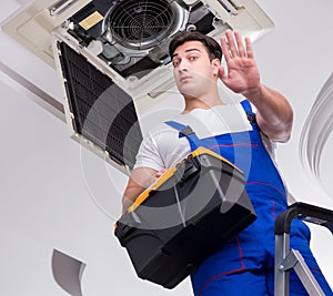 Worker repairing ceiling air conditioning unit