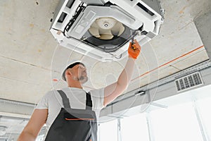 Worker repairing ceiling air conditioning unit