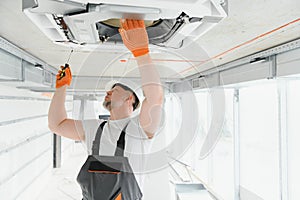 Worker repairing ceiling air conditioning unit